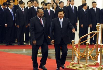 الرئيس الصيني يشير إلى رصيفه السوداني طالبا منه التقدم بصعود المنصبة قبيل عزف النشيد الجمهوري لكل من البلدين (أف ب)