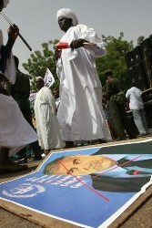 Sudanese man from Darfur walks past a portrait of the International Criminal Court (ICC) prosecutor Luis Moreno-Ocampo lying on the ground during a demonstration outside the presidential palace in Khartoum on July 17, 2008 (AFP)