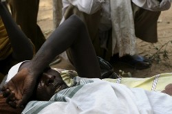 : An injured man rests on a makeshift bed at an improvised shelter outside the African Union Mission in the Sudan (AMIS) military group site in Muhajiriya, south Darfur, October 10, 2007 (Reuters)