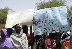 Women hold up a sign depicting the kinds of deadly attacks that forced them to leave their homes at Zam Zam camp in Sudan's North Darfur state, June 8, 2008 (Reuters)