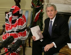 US President George W. Bush holds a copy of the book 'Tears of The Desert' written by Darfur human rights activist Dr. Halima Bashir at the conclusion of a meeting in the Oval Office of The White House in Washington, DC, on December 10, 2008 (AFP)