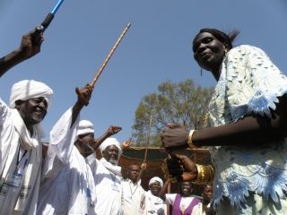 Misseriya leaders waving enthusiastically their cans, while a Dinka woman dancing during the Dinka-Misseriya conference by the end of 2008 in Aweil (photo USAID)