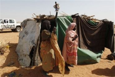 Two newly displaced Sudanese women stand by the damaged shack during an inspection visit by UNAMID peacekeepers, unseen, at Zamzam refugee camp 23 march 09