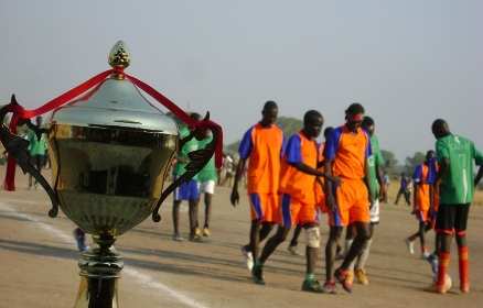 Nassir FC players (R) assist injured colleague out of the pitch as contested trophy is seen in Bor on a table, Nov. 27, 2009 (Photo by Philip Thon Aleu -- ST)