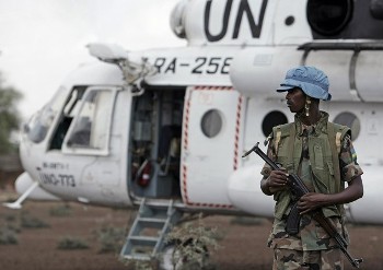 A Rwandan soldier serving with the United Nations-African Union Mission in Darfur (UNAMID) stands guard next to a UN helicopter in North Darfur (AFP)