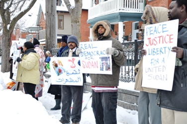 Protesters outside Sudan’s embassy in Ottawa holding banners for democratic reforms and public freedoms (photo by Lomumba Eman – ST)