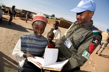 A Nigerian peacekeeper looks over a notebook with a young resident of Abu Shouk Internally Displaced Persons (IDP) Camp, North Darfur, during a UNAMID patrol (photo by UN)