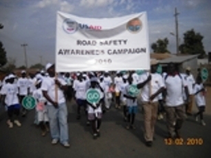 Photo of pedestrians carrying Road Safety Banner by Hellen Kiconco