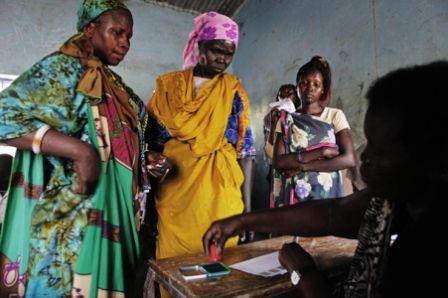 A Sudanese election official stamps a ballot paper as women vote in the town of Malakal, in Upper Nile state, April 11, 2010. (Reuters)