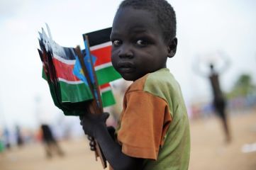 A Sudanese boy, holds a bunch of southern Sudan flags that he and other street children picked up from the ground, after a political rally in Juba on April 09, 2010 (Getty)