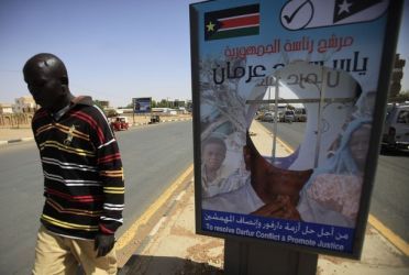 A man walks past the deliberate defacing of election campaign posters of Yasir Arman, the candidate for SPLM, in Khartoum April 1, 2010. (Reuters)