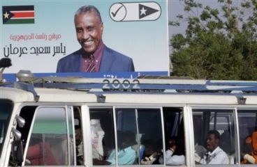 Sudanese in a public bus pass under a billboard for former candidate who boycotted the elections,Yasir Arman,