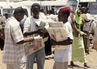 Sudanese newspaper vendors talk to each other at a bus station in Khartoum, Sudan (AP)