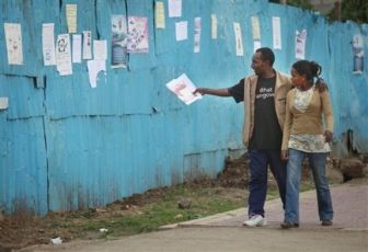 An Ethiopian couple walks past election posters set on a metal wall, in Addis Ababa, Ethiopia, (AP)