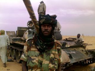 A rebel from JEM poses in front of a tank captured by the rebel group during a battle near Adeela Mountains near Muhajariyya, south Darfur ealier this month