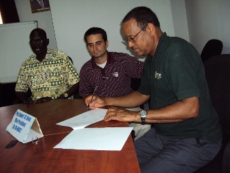 Prof. Agrey A. Majok (L) of Dr. John Memorial University, Joseph King of Texas A&M University look on as Prof.  Kamal Mohamed of State University of New York signs the agreement of collaboration in Bor on Tuesday, June 15, 2010 (ST)