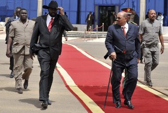 Sudan's President Omar Hassan al-Bashir (2nd R) walks with First Vice President Salva Kiir Mayardit (L) as he prepares to leave for Chad, in Khartoum July 21, 2010 (Reuters)