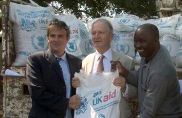 . Henry Bellingham (C) is assisted by WFP's Deputy Co-ordinator for South Sudan,Mr. Wurie Alghassim (L)