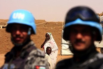An internally displaced woman smiles while members of the Jordanian peacekeeping forces from the United Nations-African Union Mission in Darfur (UNAMID) patrol at Abu Shouk IDP's camp for internally displaced people in Al Fasher, northern Darfur (Reuters)