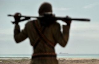 A powerful Somali pirate chief stands on a beach overlooking a hijacked ship anchored off the coast of the east African nation. (AFP)