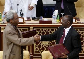 Sudan government chief negotiator Amin Hassan Omer (L) and rebel JEM top negotiator  Ahmed Tugod exchange agreements in Doha February 23, 2010.  (Reuters)