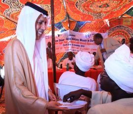 Qatari Minister of State for Foreign Affairs Ahmed bin Abdullah Al-Mahmoud (L), offers nuts to displaced Sudanese during a meeting in Nyala, on November 29, 2010. (Getty)