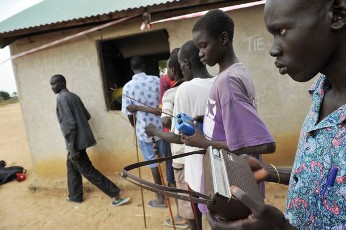 A resident of the remote south central Southern Sudan village of Nyal listens to news of the referendum as he waits in line to register his name with Referedum workers at a local school on November 15, 2010 (AFP)
