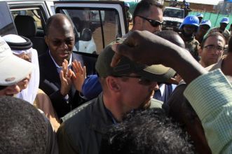 Djibril Bassole (L) reacts to protesters as he is ushered back to his vehicle after leaving a meeting that was disrupted by protesters in Nyala, South Darfur November 30, 2010. (Reuters)