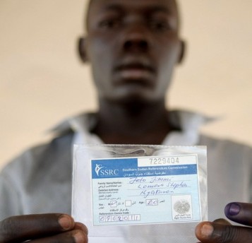 A Southern Sudan voter displays his voter registration card at the John Garang de Mabior mausoleum in Juba, December 6, 2010 (Reuters)