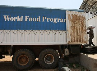A worker loading a bag of food into a World Food Program (WFP) truck in el-Fasher (AFP)
