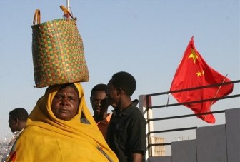 FILE - This Feb. 1, 2007 file photo shows a Sudanese woman walking past one of the Chinese flags lining the streets of Khartoum, ahead of a historic visit to Sudan by President Hu Jintao of China (AP)
