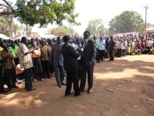 Adel Sandrai (left), W. Equatoria Minister for Education, and Bashir Bandi (right), Maridi County MP, embrace each at a renconciliation rally as Bishop Badi watches. January 5, 2011 (ST)