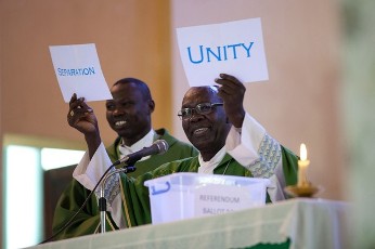 A priest at Juba's cathedral shows signs reading 'Unity' and 'Separation' during Sunday mass on January 16, 2011 (AFP)