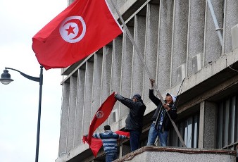 Tunisian demonstrators standing above the Interior ministry's main door in Tunis on January 14, 2011 (AFP)