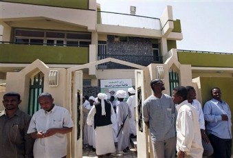 FILE - Greeters pass a poster with a picture of Islamist opposition leader Hassan Turabi and Arabic writing that reads 