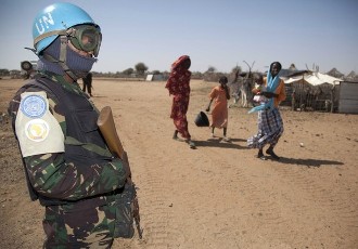 Women with children walk near a soldier of Darfur's joint U.N./African Union UNAMID peacekeeping force (Reuters)