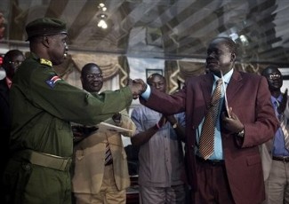 SPLA Brig. Gen. Michael Majur, left, shakes hands with Abraham Thon, right, representative of rebel leader Lt. Gen. George Athor, after signing a ceasefire agreement in Juba, Jan. 5, 2011. (AP)