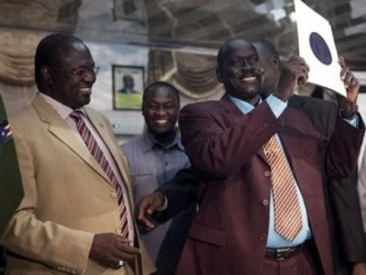 Riek Machar (L) stands next to Abraham Thon(R) a ranking representative of Gen. George Athor, who holds up a copy of the ceasefire agreement between the SPLA and Athor's delegation in Juba, on Wednesday, Jan. 5, 2011 (AP)
