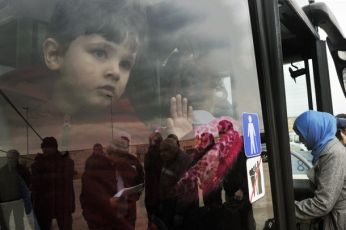 A child peers out from a bus carrying mainly Portuguese evacuees from Libya who arrived on a Greek ferry in the port of Piraeus, near Athens, on February 27, 2011 (Getty)