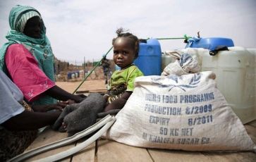 A child sits next to food rations in the Shangle Tubaya New IDP Camp in North Darfur October 17, 2010 (Reuters)