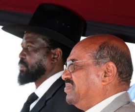 Sudanese President Omar al-Bashir (R) and southern leader Salva Kiir listen to the coutry's national anthem at Juba International airport on January 4, 2010 (Getty Images)