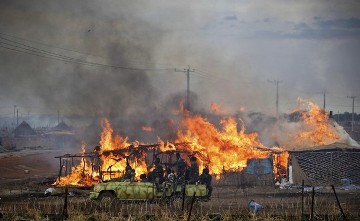 A machinegun-mounted truck manned by members of the Sudan Armed Forces (SAF) drive past burning businesses and homesteads, locally known as 