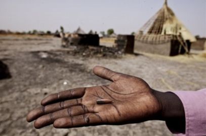 A survivor of a massacre by rebel forces on the town of Fangak displays a bullet in front of burnt houses in Fangak, southern Sudan Thursday, April 7, 2011 - (AP)