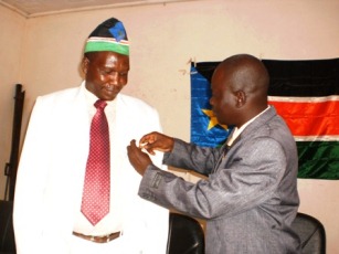 SPLM state secretary, Manase Deboi, gives SPLM's badge to Awad Kisanga