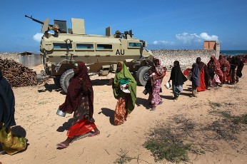 Somalis displaced from their home villages by famine and drought pass an African Union armored vehicle at a feeding center on August 16, 2011 in Mogadishu, Somalia (AFP)