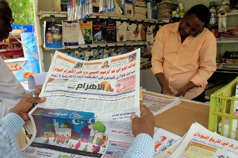 A Sudanese man reads a newspaper as he waits to pay at a kiosk in the capital Khartoum, on July 31, 2011 (AFP)