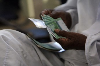 A man counts notes after receiving the new Sudanese currency at a central bank branch in Khartoum July 24, 2011 (Reuters)