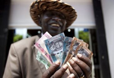 A South Sudanese man displays new currency notes outside the Central Bank of South Sudan in Juba 18 July, 2011. (Reuters)