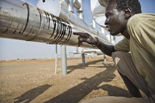 A man examines a leaking oil pipe line at a pumping station built next to his village on land that was once used for agriculture, Paloch, South Sudan, January 20, 2010 (Sven Torfinn)