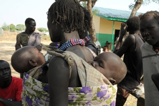 A Murle woman with two of her children on her back returns to Pibor after fleeing the town. Pibor County, Jonglei, South Sudan. Jan. 6, 2012 (ST)